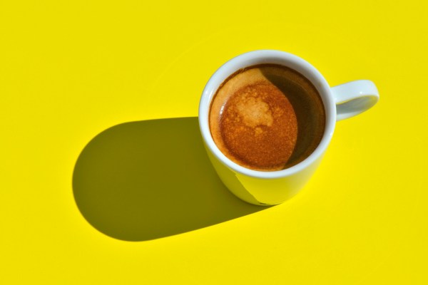 Espresso with shadow on bright yellow background.